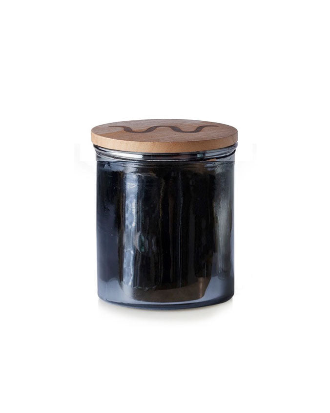 Candle with black wrapping and King Ranch logo on lid  in front of white background.