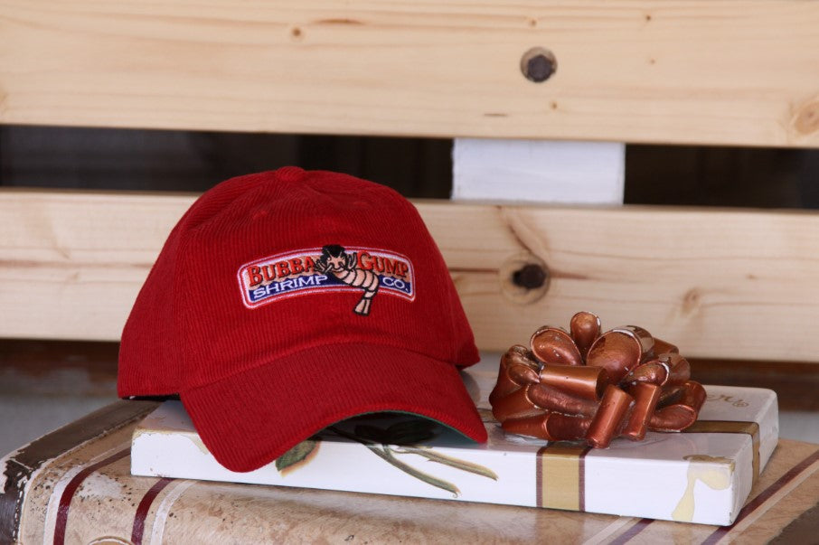 Limited edition red Bubba Gump cap placed on top of a box of chocolates that is sitting on a bench.